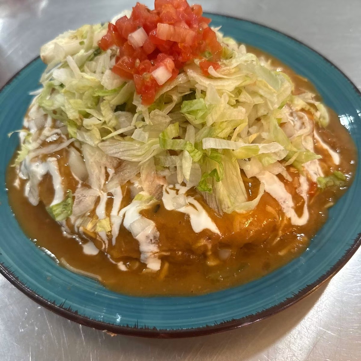 A stuffed sopapilla smothered in Licha's homemade green chili, topped with lettuce and tomatoes